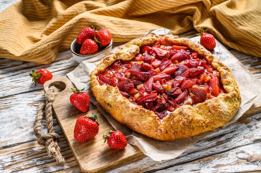 Baked galette with strawberry and rhubarb, pie on the table. Homemade pastry